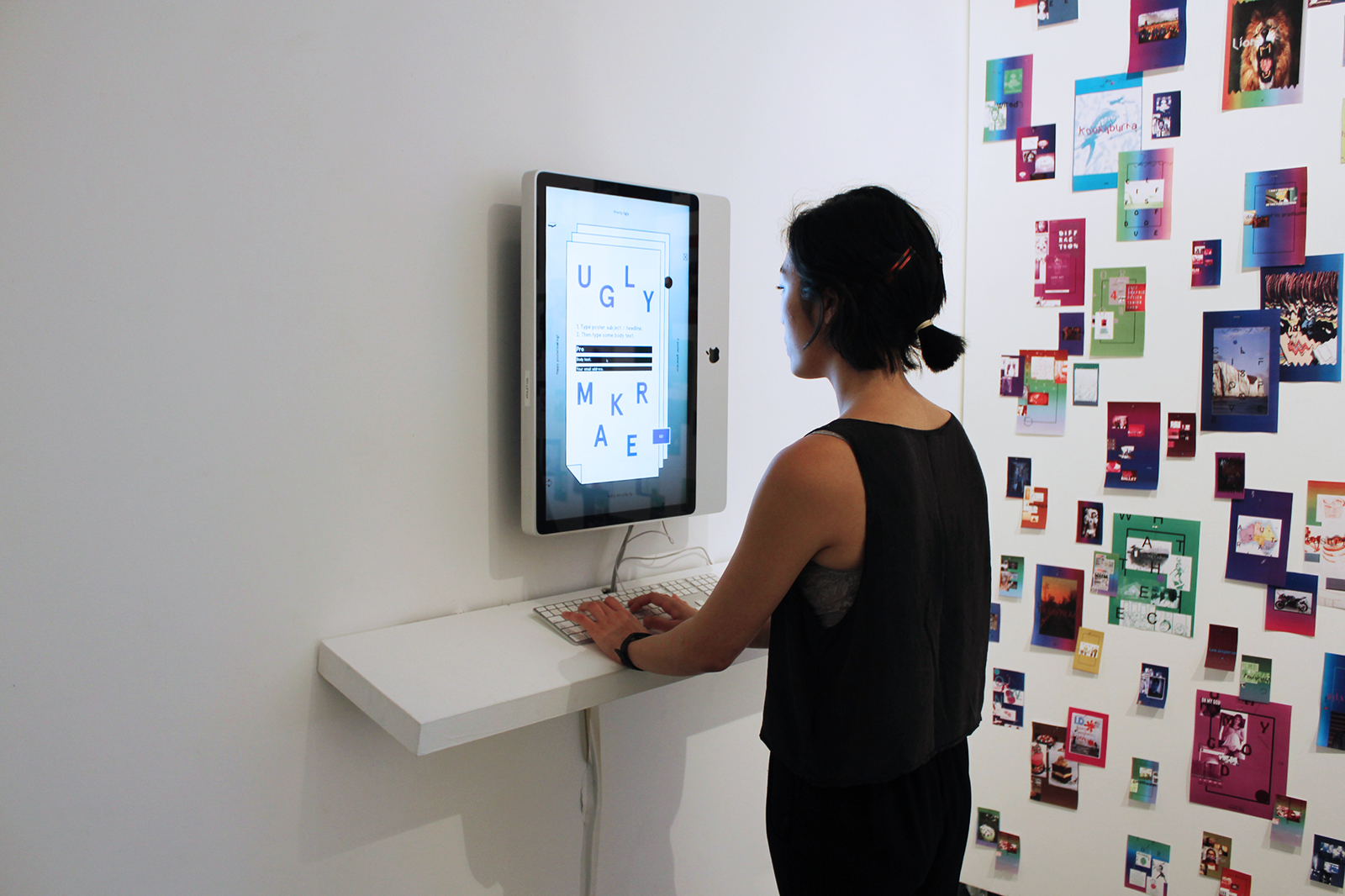 A young Asian woman inputs text in the main interface of Uglymaker. To her right is a wall of overlapping tiny colorful posters generated by the Uglymaker.